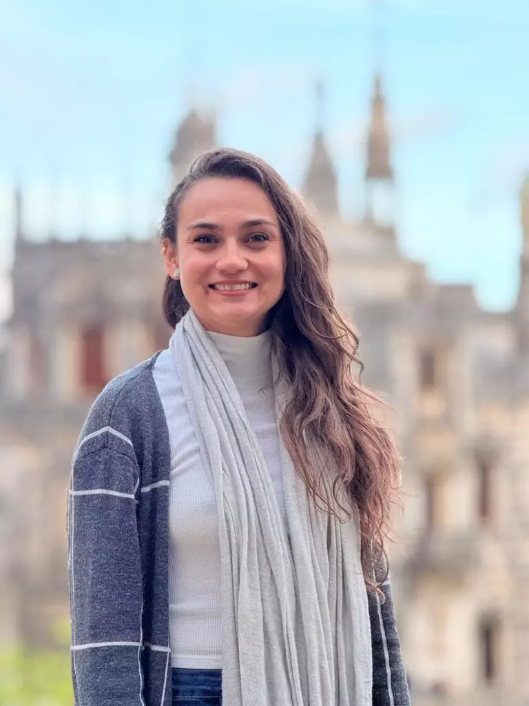Danyella Santos, Operations Coordinator at Yes, You Deserve, smiling in front of the iconic architecture of Sintra, Portugal. Dedicated to organizing personalized private tuk tuk tours for unforgettable experiences.