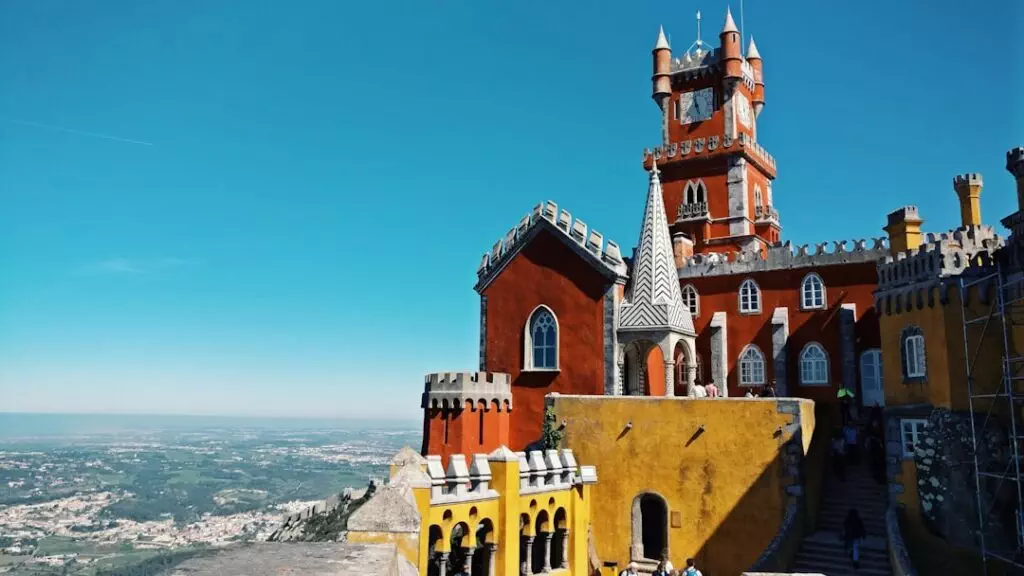 Breathtaking view of the colorful Pena Palace in Sintra, Portugal, with panoramic landscape in the background — a must-see on a private Yes, You Deserve tuk tuk tour.