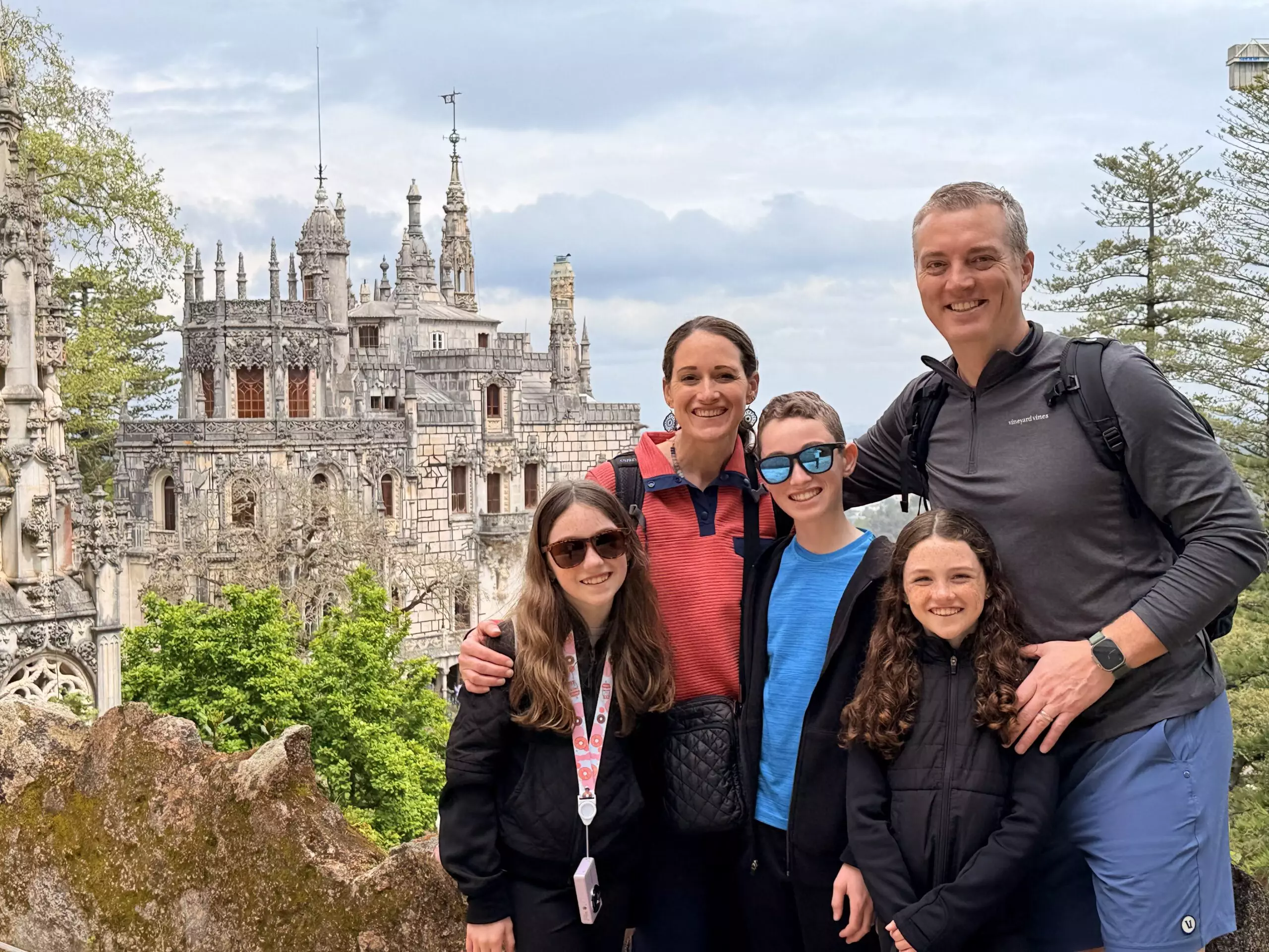 Family doing a tour inside quinta da regaleira with the palace behing after the initiation well