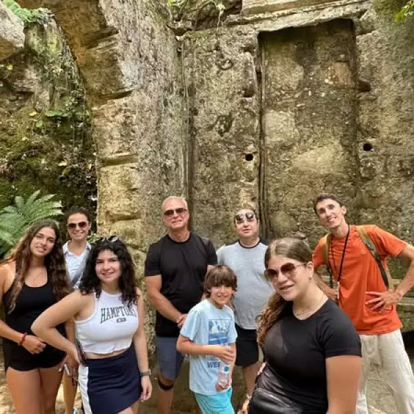 Private guided tour in Sintra’s mystical Quinta da Regaleira with Daniel Ponce and a family group exploring historical ruins surrounded by lush greenery.
