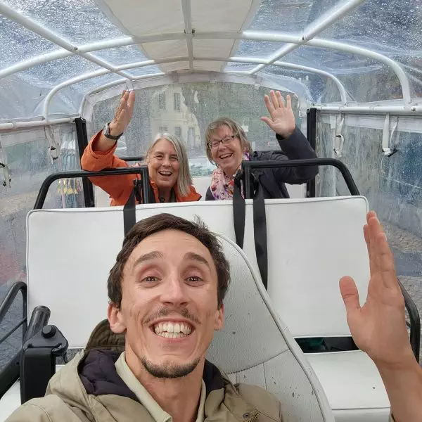 Smiling tourists on a rainy day enjoying a private tuk tuk tour in Sintra with Daniel Ponce from Yes, You Deserve! – covered electric tuk tuk ensuring comfort in all weather conditions.