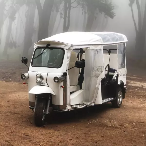 A white electric tuk-tuk parked on a quiet road in Sintra, Portugal, ready to take guests on a scenic and eco-friendly adventure with Yes, You Deserve. Surrounded by lush greenery and cobblestone paths, it offers a charming and sustainable way to explore the town.