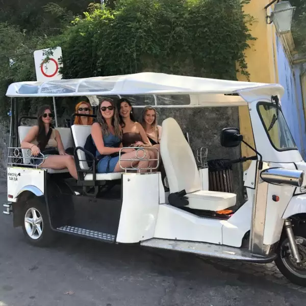 Group of friends smiling on an electric tuk tuk tour in Sintra, Portugal, ready to explore the town’s magical streets with Yes, You Deserve.