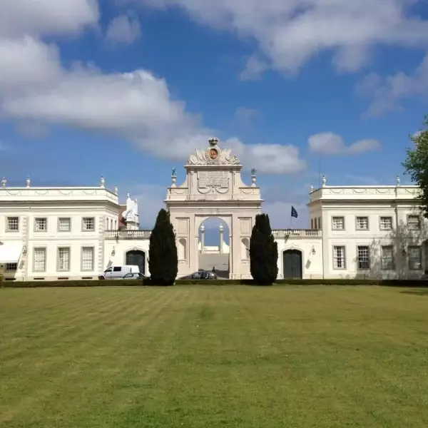 Front view of Palácio de Seteais in Sintra, Portugal, with neoclassical architecture, central archway, manicured lawn, and blue sky – luxury hotel Tivoli Palácio de Seteais.