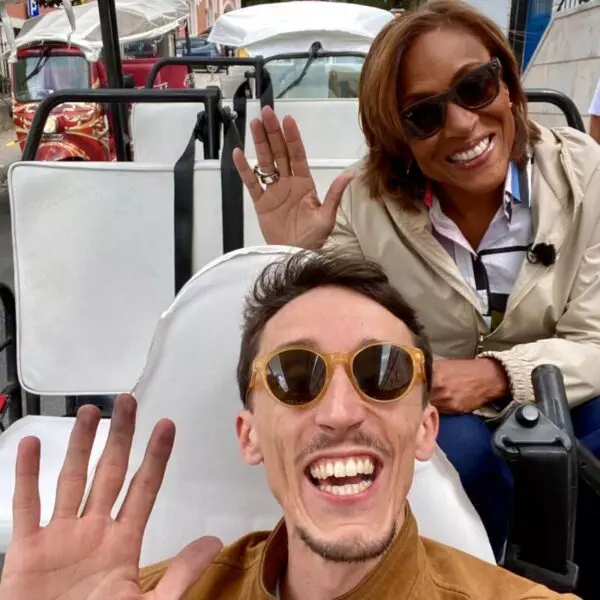 Robin Roberts and tour guide Daniel Ponce smiling and waving from inside a white electric tuk-tuk during a Yes, You Deserve tour in Sintra, Portugal. Their joyful energy highlights the friendly and personalized experience of the tour.