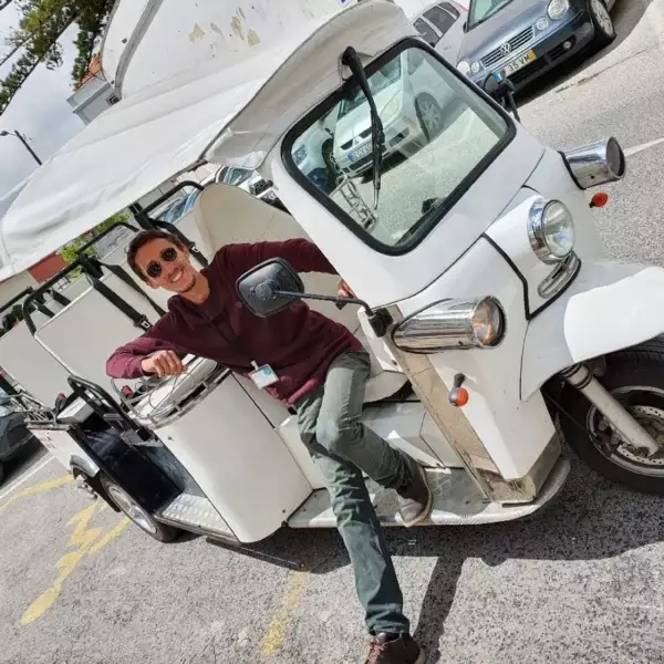 Daniel Ponce, smiling and wearing sunglasses, poses confidently in the driver’s seat of a white electric tuk-tuk during a Yes, You Deserve tour in Sintra, ready to lead another unforgettable adventure.
